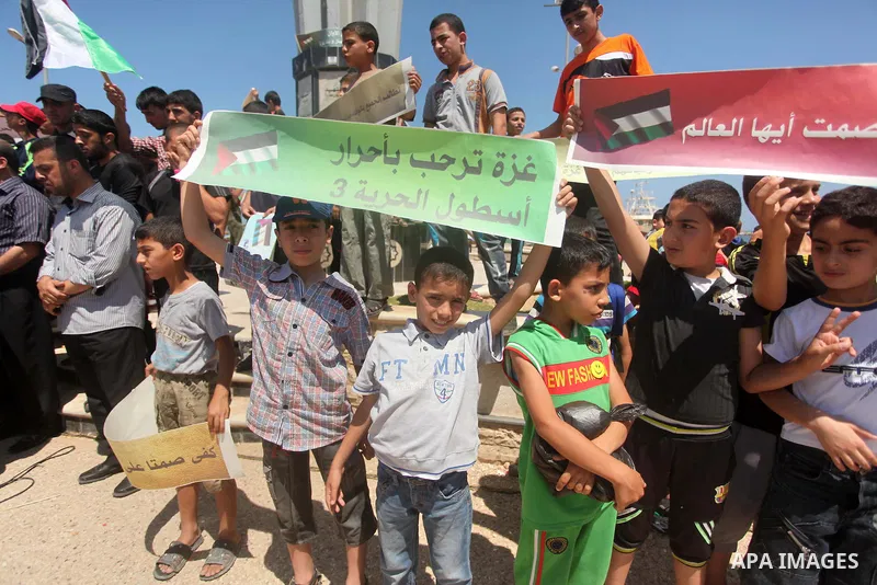 Palestinian children hold flags and banners during a rally to show solidarity with Third Freedom Flotilla and to demand break the Israeli blockade on the Gaza strip in Gaza port on June 10, 2015. The flotilla is the thir...