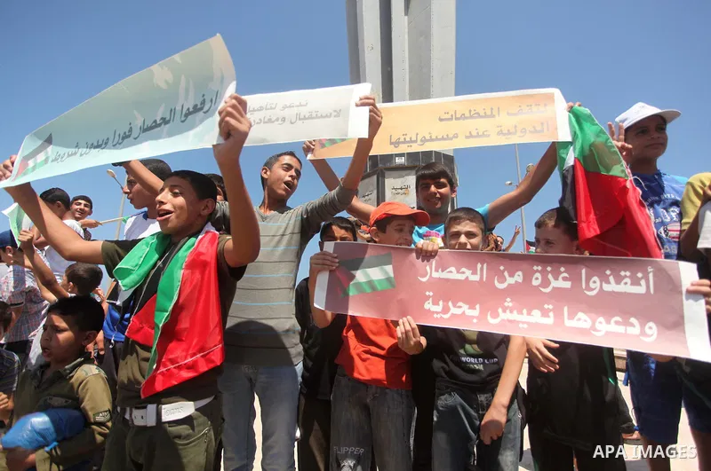 Palestinian children hold flags and banners during a rally to show solidarity with Third Freedom Flotilla and to demand break the Israeli blockade on the Gaza strip in Gaza port on June 10, 2015. The flotilla is the thir...