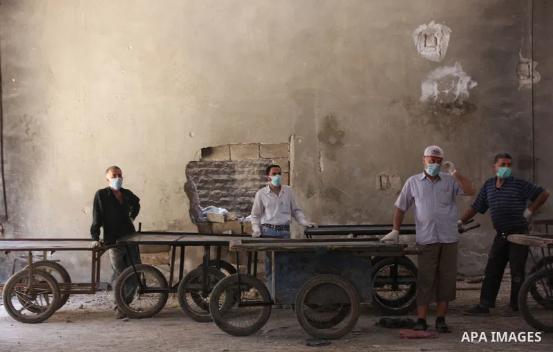 Workers wait near their carts to carry the bodies of dead fighters loyal to Free Syrian Army during an exchange of dead bodies between Free Syrian Army and Syrian Government forces, in Bustan al-Qasr district in the east...