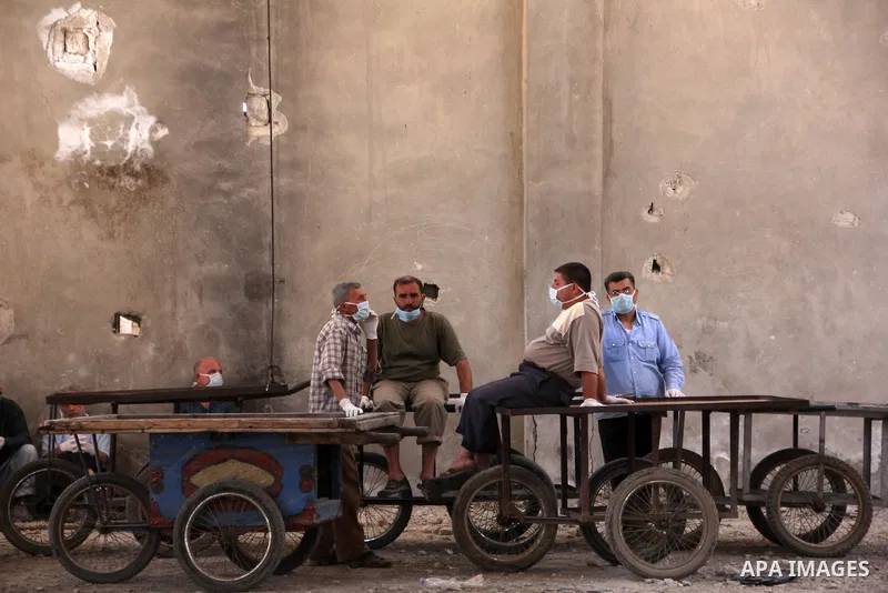 Workers wait near their carts to carry the bodies of dead fighters loyal to Free Syrian Army during an exchange of dead bodies between Free Syrian Army and Syrian Government forces, in Bustan al-Qasr district in the east...