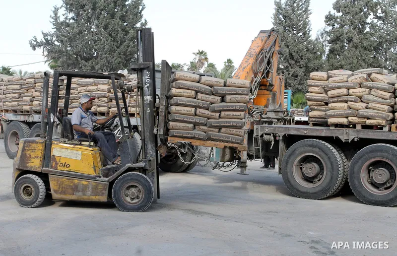 Palestinian workers offload a truck loaded with cement after it entered from Egypt through the Rafah border crossing in southern Gaza Strip, on June 13, 2015. Egyptian authorities for the first time since the expulsion o...