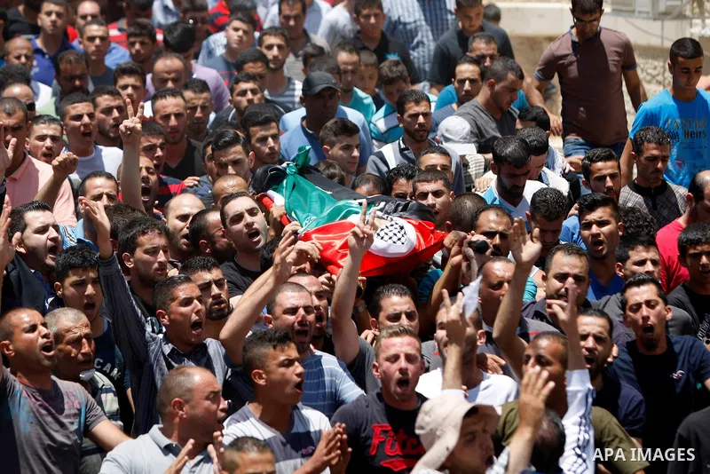 Mourners carry the body of 21-year-old Palestinian Abdallah Ghanayem, during his funeral in the village of Kafr Malik, northeast of Ramallah on June 14, 2015. An army spokesman said that the Palestinian had died after he...