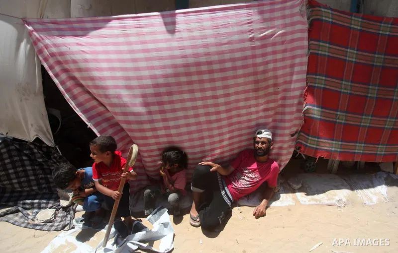 Palestinians sit in front a tent outside a UN-run school in Gaza City on June 18, 2015. "UNRWA" announced that they are closed the last affiliate accommodation centers in the Gaza Strip after paid to the displaced Palest...