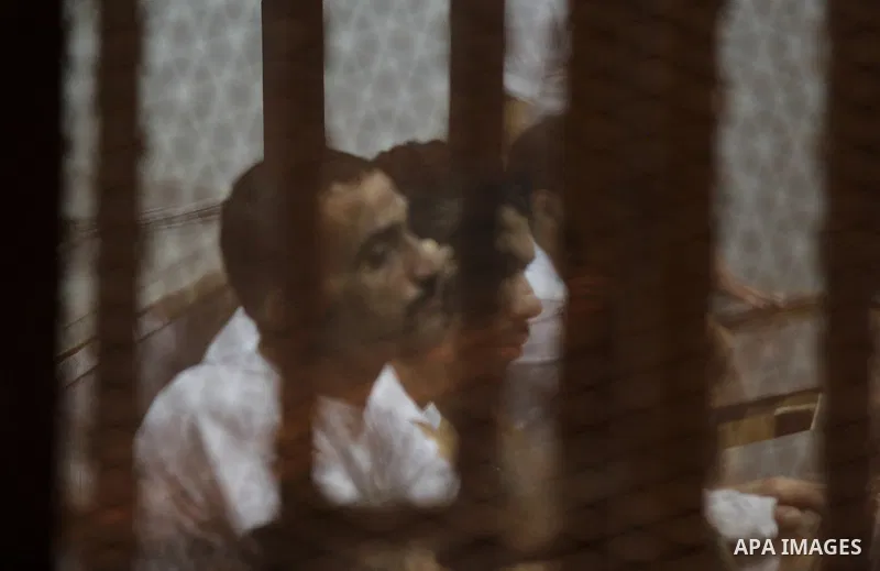 Egyptian defendants react behind bars after the verdict in their retrial over a 2012 stadium riot in the canal city of Port Said that left 74 people dead, in a court in the Egyptian capital, Cairo on June 20, 2015. Photo...