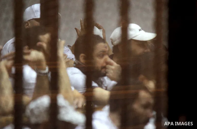 Egyptian defendants react behind bars after the verdict in their retrial over a 2012 stadium riot in the canal city of Port Said that left 74 people dead, in a court in the Egyptian capital, Cairo on June 20, 2015. Photo...