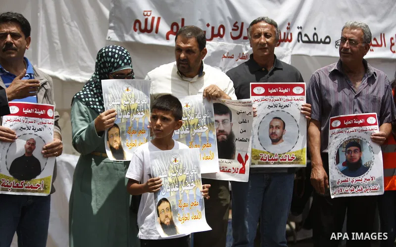Palestinians hold placard during a protest in support of Palestinian Khader Adnan, a senior member of the Islamic Jihad who was jailed in Israel without a trial, in the West Bank city of Ramallah on June 25, 2015. Photo...