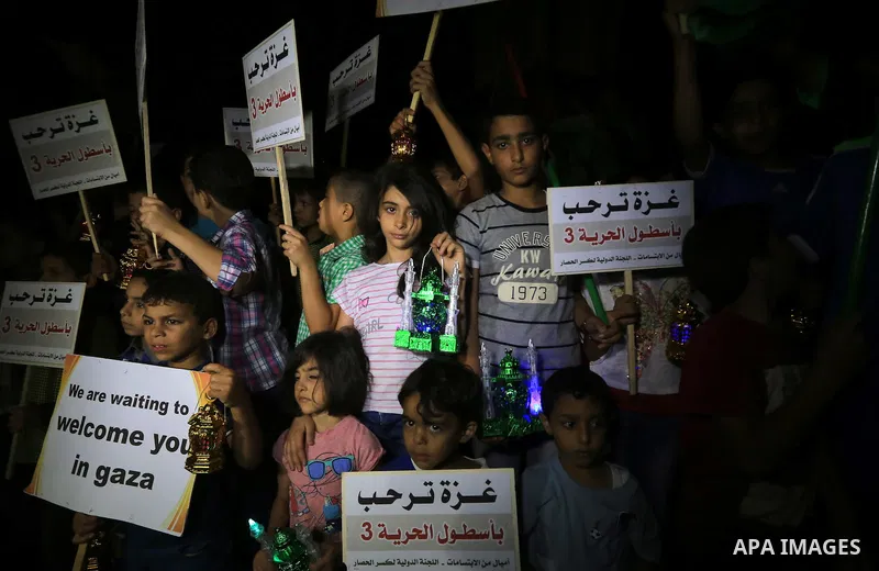 Palestinians children hold placards and wave their national flag during a rally to show support for activists aboard a flotilla of boats who are soon to set sail for Gaza in a fresh bid to break Israel's blockade of the...