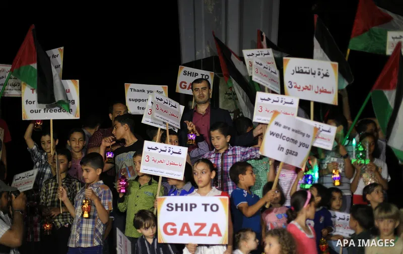 Palestinians children hold placards and wave their national flag during a rally to show support for activists aboard a flotilla of boats who are soon to set sail for Gaza in a fresh bid to break Israel's blockade of the...