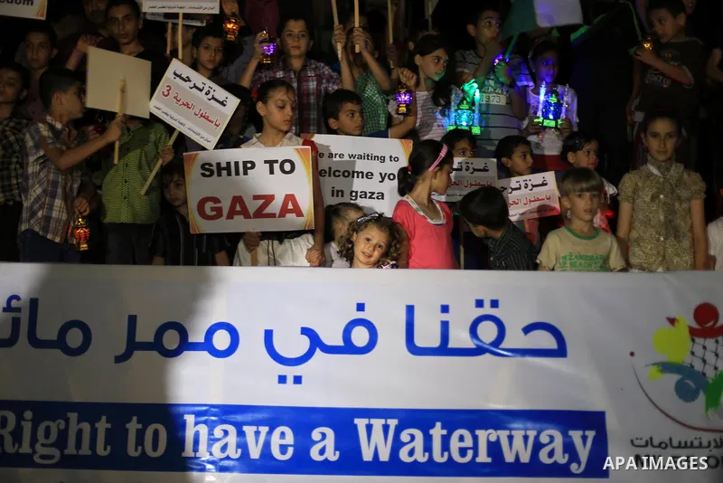 Palestinians children hold placards and wave their national flag during a rally to show support for activists aboard a flotilla of boats who are soon to set sail for Gaza in a fresh bid to break Israel's blockade of the...