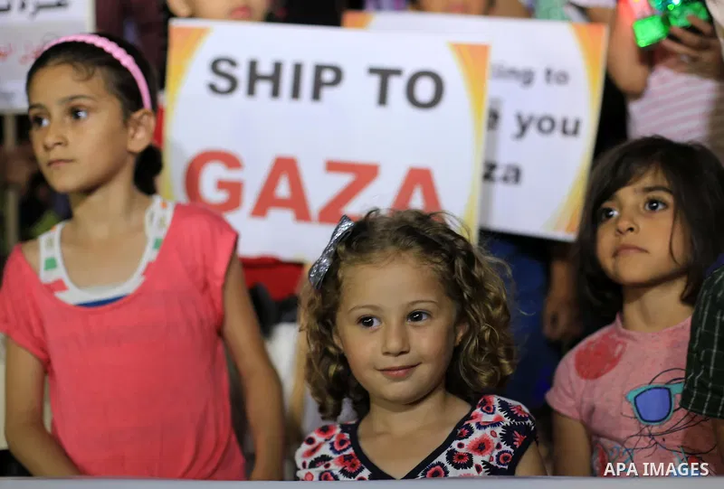 Palestinians children hold placards and wave their national flag during a rally to show support for activists aboard a flotilla of boats who are soon to set sail for Gaza in a fresh bid to break Israel's blockade of the...