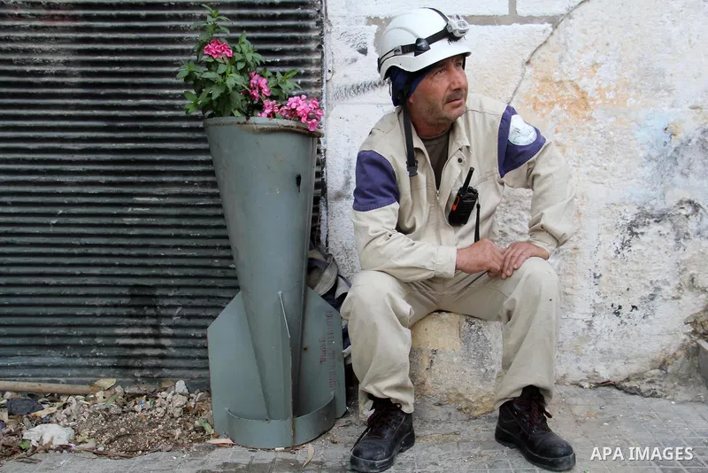 Mohammed Mashadi, a 40-year-old Syrian civil defense member, sits next to flowers planted in remains of unexploded bomb, that was fired by Syrian government airforce, in a street in Bab al-Nairab district in the northern...