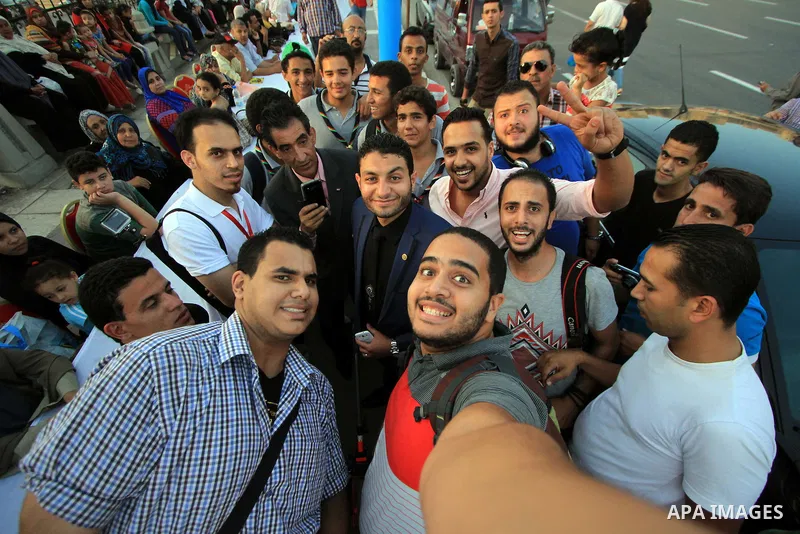 Egyptian youths take a picture next to an Iftar table as they wait to break their daytime fast, during the Muslim holy month of Ramadan, in Egypt s Mediterranean city of Alexandria, Friday, June 26, 2015. Alexandria is s...
