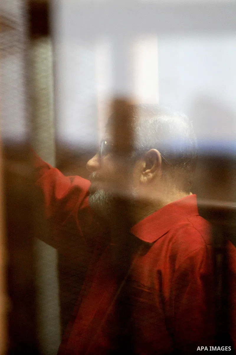 Former Egyptian president Mohammed Morsi stands behind bars during his trail in a court in Cairo on June 27, 2015. Photo by Amr Sayed