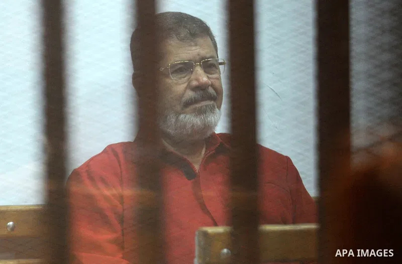 Former Egyptian president Mohammed Morsi stands behind bars during his trail in a court in Cairo on June 27, 2015. Photo by Amr Sayed