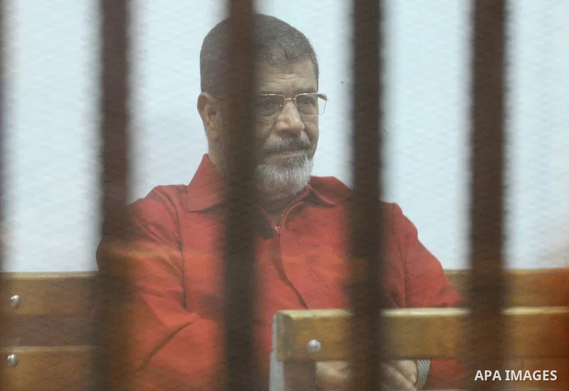 Former Egyptian president Mohammed Morsi stands behind bars during his trail in a court in Cairo on June 27, 2015. Photo by Amr Sayed