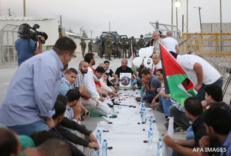 Palestinian protesters break their fast during a protest in support of prisoners demanding for their release from Israeli jails, outside Ofer Israeli military prison, near the West Bank city of Ramallah on June 27, 2015....