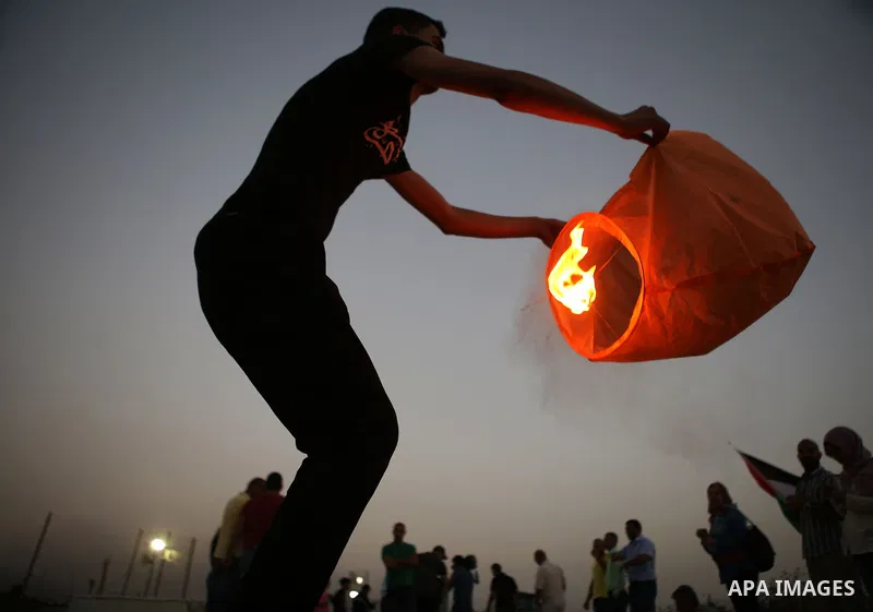 Palestinian protesters hold balloons and posters of prisoners during a protest demanding for their release from Israeli jails, outside Ofer Israeli military prison, near the West Bank city of Ramallah on June 27, 2015. P...