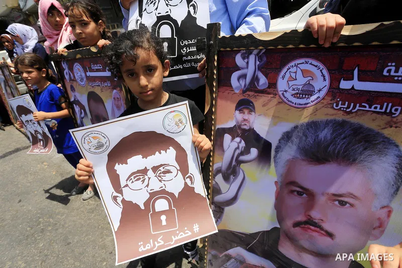 Palestinians hold posters of Islamic Jihad member Khader Adnan, a senior member of Islamic Jihad, under administrative detention in an Israeli jail, during a protest calling for the release him, in Gaza city on June 28,...