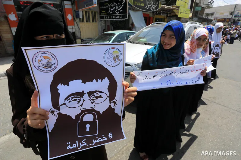 Palestinians hold posters of Islamic Jihad member Khader Adnan, a senior member of Islamic Jihad, under administrative detention in an Israeli jail, during a protest calling for the release him, in Gaza city on June 28,...