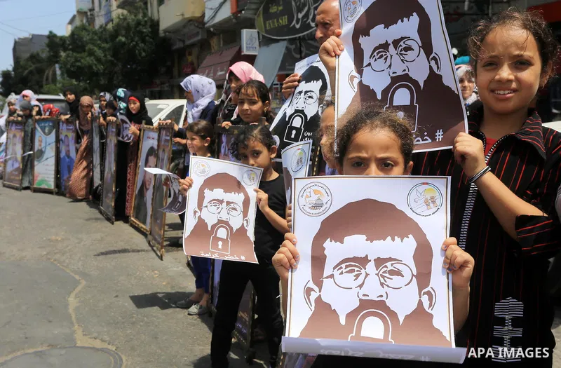 Palestinians hold posters of Islamic Jihad member Khader Adnan, a senior member of Islamic Jihad, under administrative detention in an Israeli jail, during a protest calling for the release him, in Gaza city on June 28,...