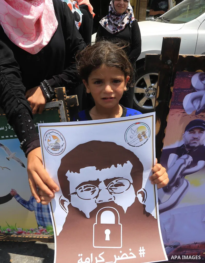 Palestinians hold posters of Islamic Jihad member Khader Adnan, a senior member of Islamic Jihad, under administrative detention in an Israeli jail, during a protest calling for the release him, in Gaza city on June 28,...