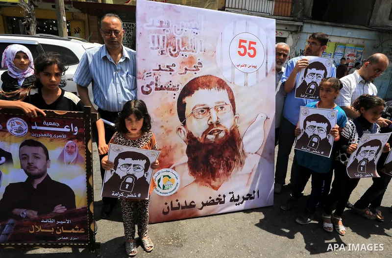 Palestinians hold posters of Islamic Jihad member Khader Adnan, a senior member of Islamic Jihad, under administrative detention in an Israeli jail, during a protest calling for the release him, in Gaza city on June 28,...