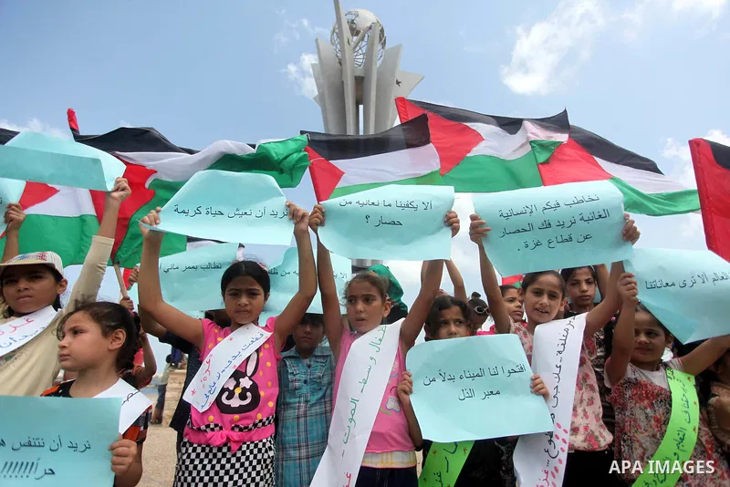 Palestinians children hold placards and wave their national flag during a rally to show support for activists aboard a flotilla of boats who are soon to set sail for Gaza in a fresh bid to break Israel's blockade of the...
