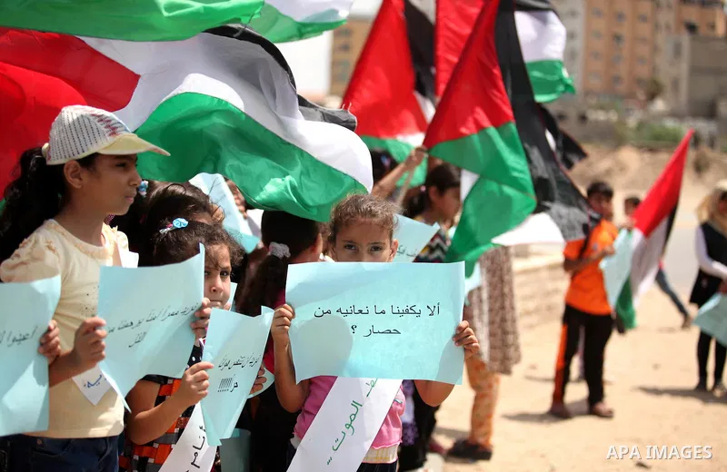 Palestinians children hold placards and wave their national flag during a rally to show support for activists aboard a flotilla of boats who are soon to set sail for Gaza in a fresh bid to break Israel's blockade of the...