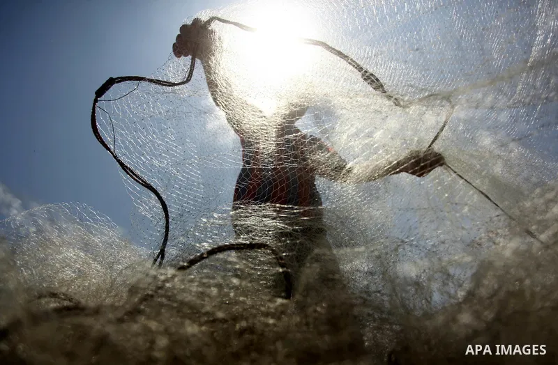 A Palestinian fisherman fixes his net at the Gaza seaport, on June 28, 2015. Photo by Ashraf Amra