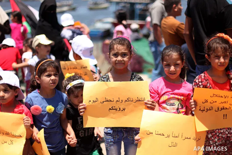 Palestinian children hold banners and their national flag during a protest against the Israeli blocking of a boat of foreign activists from reaching Gaza, at the Seaport of Gaza City June 29, 2015. Israel said on Monday...