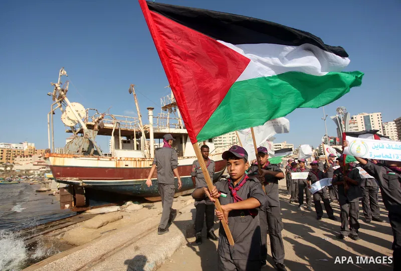 Palestinian scouts hold banners and their national flag during a protest against the Israeli blocking of a boat of foreign activists from reaching Gaza, at the Seaport of Gaza City June 29, 2015. Israel said on Monday it...