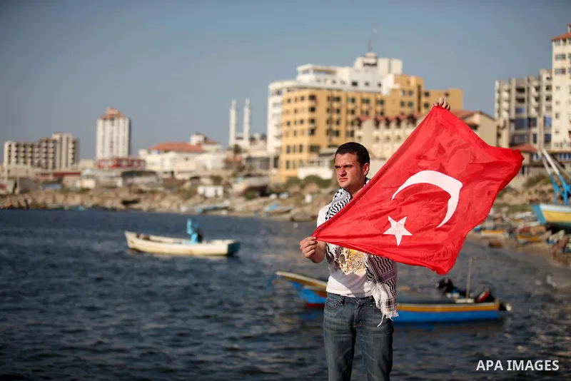 A Palestinian man holds Turkish flag during a protest against the Israeli blocking of a boat of foreign activists from reaching Gaza, at the Seaport of Gaza City June 29, 2015. Israel said on Monday it had blocked a boat...