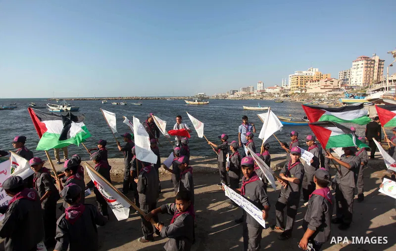Palestinian scouts hold banners and their national flag during a protest against the Israeli blocking of a boat of foreign activists from reaching Gaza, at the Seaport of Gaza City June 29, 2015. Israel said on Monday it...