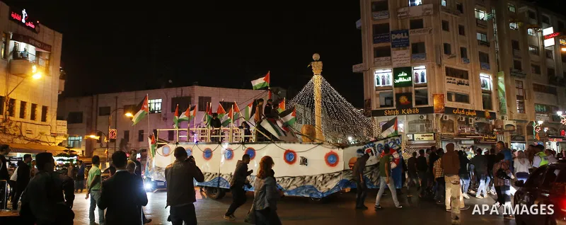 Palestinians walk next to a model of a ship during a rally in solidarity with activists aboard a flotilla of boats who are soon to set sail for Gaza in a fresh bid to break Israel's blockade of the territory, in the West...
