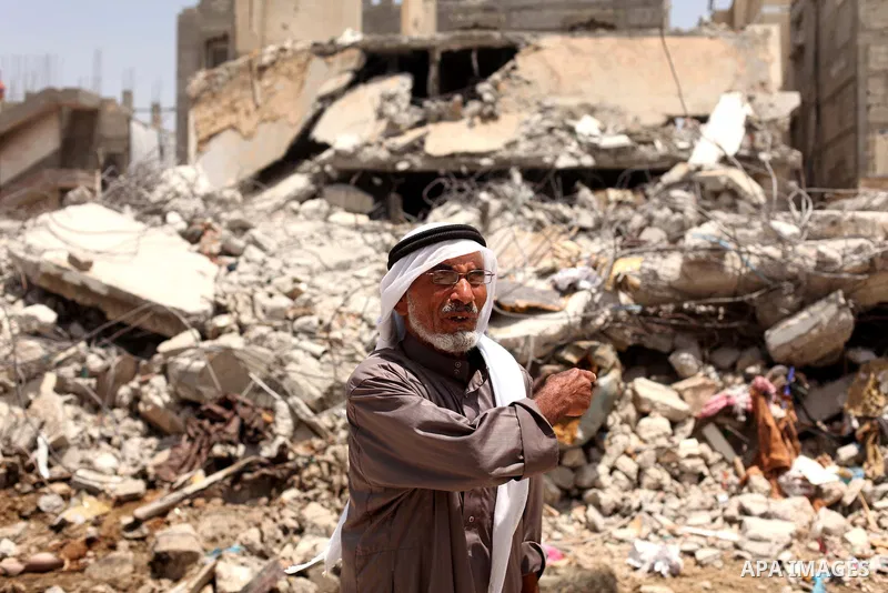 A Palestinian man looks on as she stands in front of the ruins of his house, that witnesses said was destroyed by Israeli shelling during a 50-day war last summer, in Khan Younis in the southern Gaza Strip July 2, 2015....