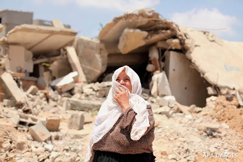 A Palestinian woman looks on as she stands in front of the ruins of her house, that witnesses said was destroyed by Israeli shelling during a 50-day war last summer, in Khan Younis in the southern Gaza Strip July 2, 2015...