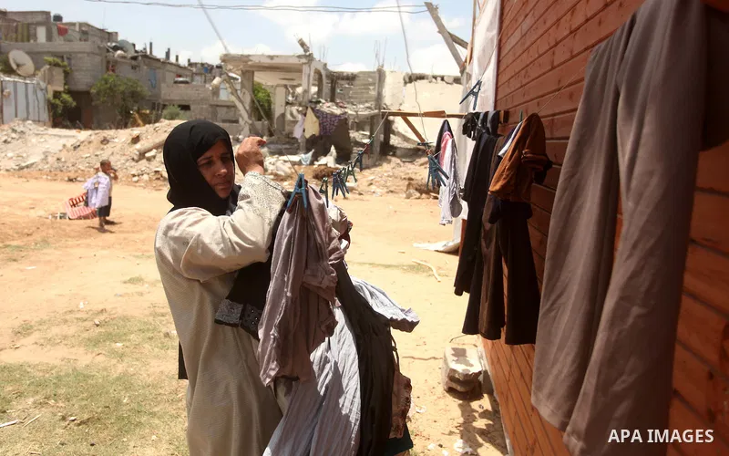A Palestinian woman collects laundry near the ruins of her house, that witnesses said was destroyed by Israeli shelling during a 50-day war last summer, in Khan Younis in the southern Gaza Strip July 2, 2015. Robert Turn...