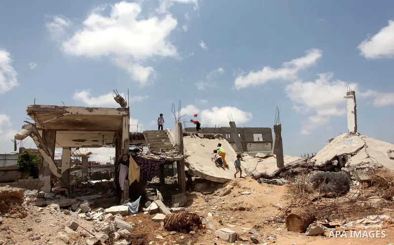 Palestinian childern play on the ruins of houses, that witnesses said were destroyed by Israeli shelling during a 50-day war last summer, in Khan Younis in the southern Gaza Strip July 2, 2015. Robert Turner has no quick...