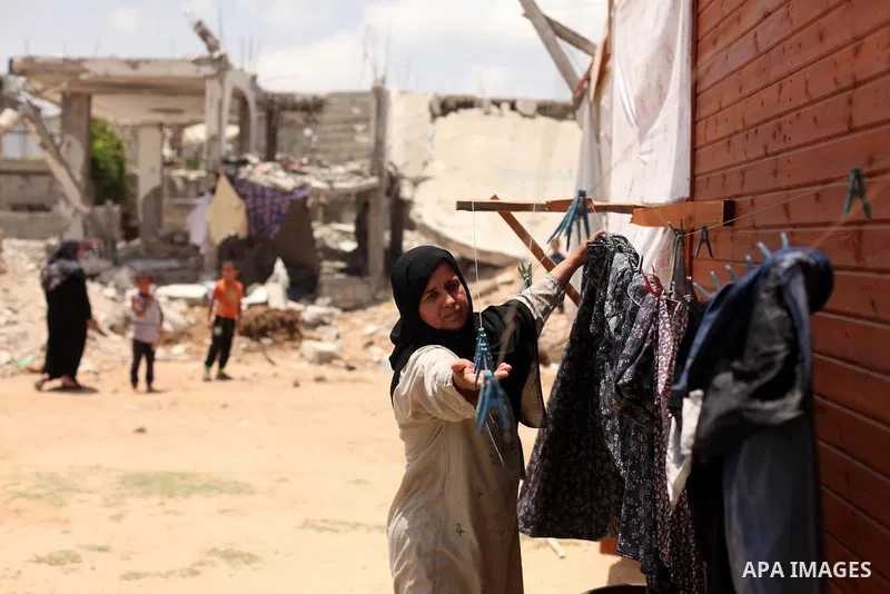 A Palestinian woman collects laundry near the ruins of her house, that witnesses said was destroyed by Israeli shelling during a 50-day war last summer, in Khan Younis in the southern Gaza Strip July 2, 2015. Robert Turn...