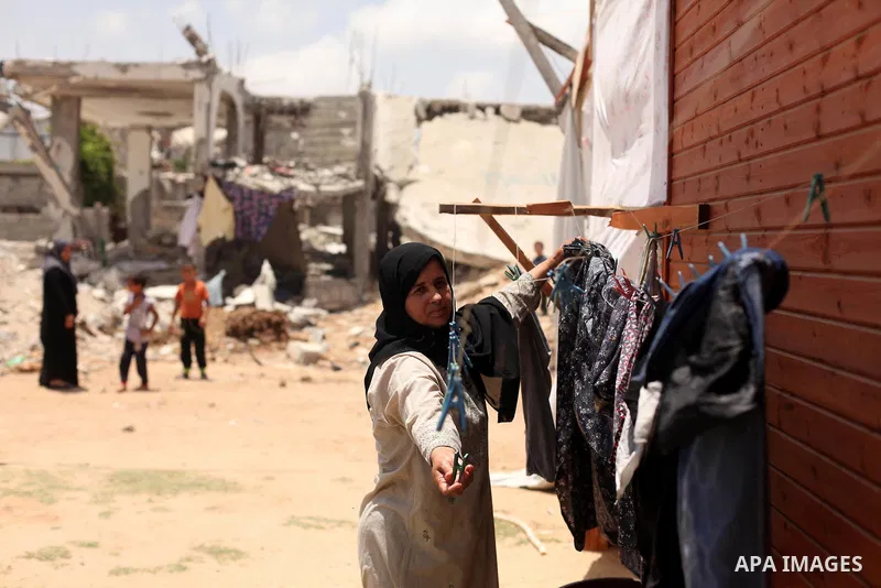 A Palestinian woman collects laundry near the ruins of her house, that witnesses said was destroyed by Israeli shelling during a 50-day war last summer, in Khan Younis in the southern Gaza Strip July 2, 2015. Robert Turn...