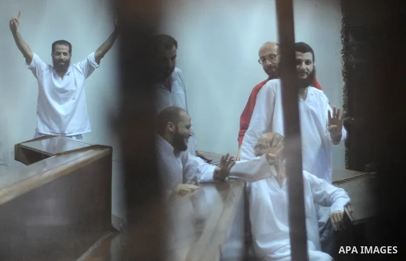 Egyptian Muslim Brotherhood defendants stand behind the bars during their trial, along with ousted Islamist president Mohamed Morsi (unseen), in Cairo on July 04, 2015. Photo by Amr Sayed