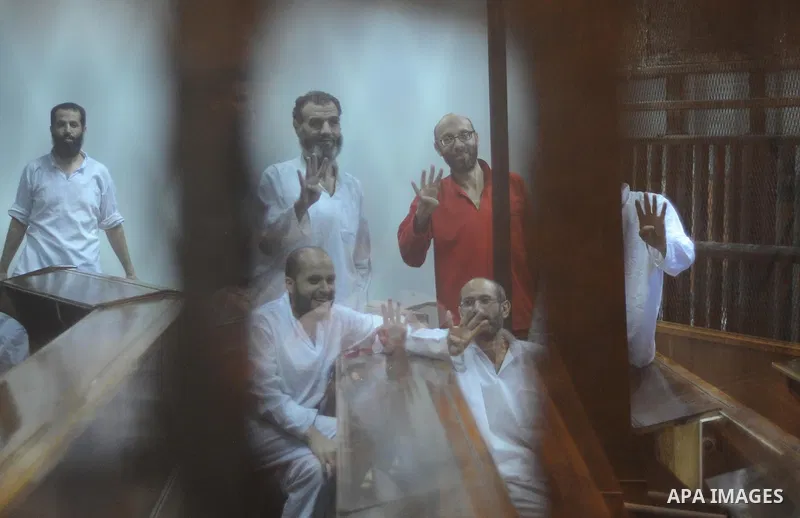 Egyptian Muslim Brotherhood defendants stand behind the bars during their trial, along with ousted Islamist president Mohamed Morsi (unseen), in Cairo on July 04, 2015. Photo by Amr Sayed