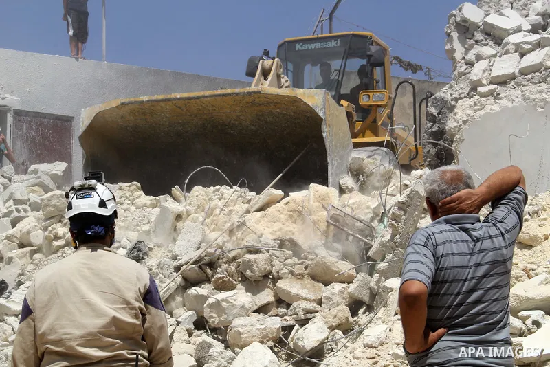 Syrian rescue workers use a bulldozer to remove the debris of a building after two days of a reported bomb barrel attack by Syrian government forces, in Sheikh Khadr rebel held district in the northern Syrian city of Ale...