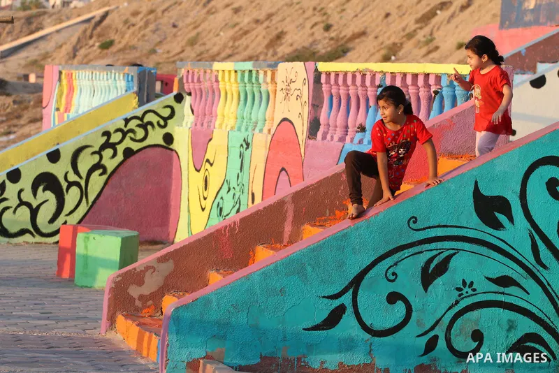 Palestinian children play on a colour stones, at the Marine Park on a beach Gaza City, on July 11, 2015. That was painted by local artists on the Gaza sea in an attempt to bring more vibrant colours to the city. Photo by...