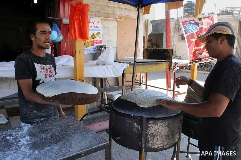 A Palestinian man bakes loaves of bread in his traditional mud oven in Rafah in the southern Gaza Strip, on July 12, 2015. Photo by Abed Rahim Khatib
