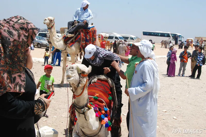 An Egyptian woman rides a camel in front of the Giza pyramids, on the third day of Eid al-Fitr holiday which marks the end of the Muslim holy month of Ramadan, in Cairo on July 19, 2015. Photo by Amr Sayed