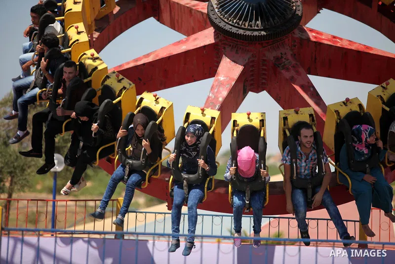 Palestinians take a ride at an amusement park on the third day of Eid al-Fitr holiday which marks the end of the Muslim holy month of Ramadan, in Gaza City on July 19, 2015. Photo by Ashraf Amra