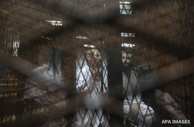 Egyptian Muslim Brotherhood defendants stand behind the bars during their trial, at the police academy on the outskirts of the capital, on July 21, 2015. Cairo criminal court resumed proceedings in the 'Qatar espionage t...