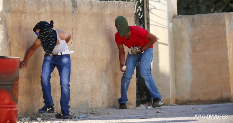 Palestinian protesters take cover during clashes with Israeli soldiers following a protest against the construction of settlements and the confiscation of the Palestinian land, in the West Bank village of Silwad, near Ra...