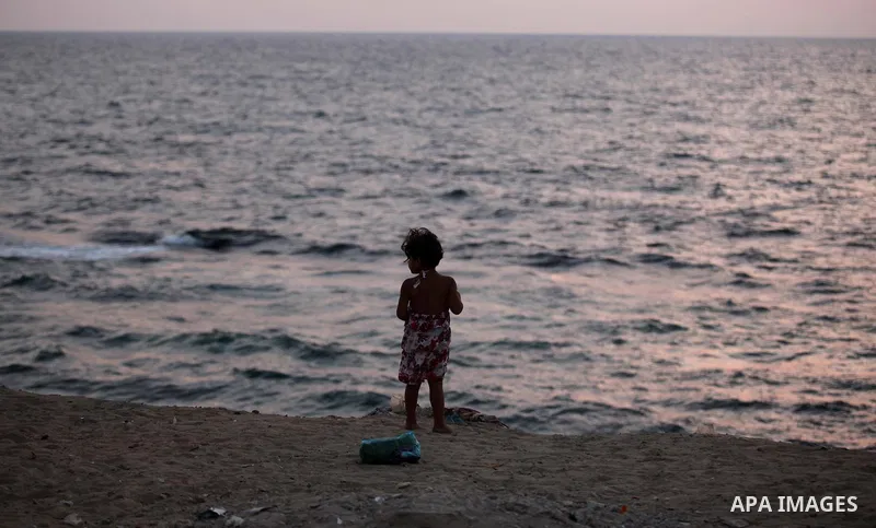 A Palestinian girl stands along the beach of Gaza city during the sunset, on July 27, 2015. Independent Commission for Human Rights warned Saturday of the aggravated humanitarian situation in Gaza due to continued electr...